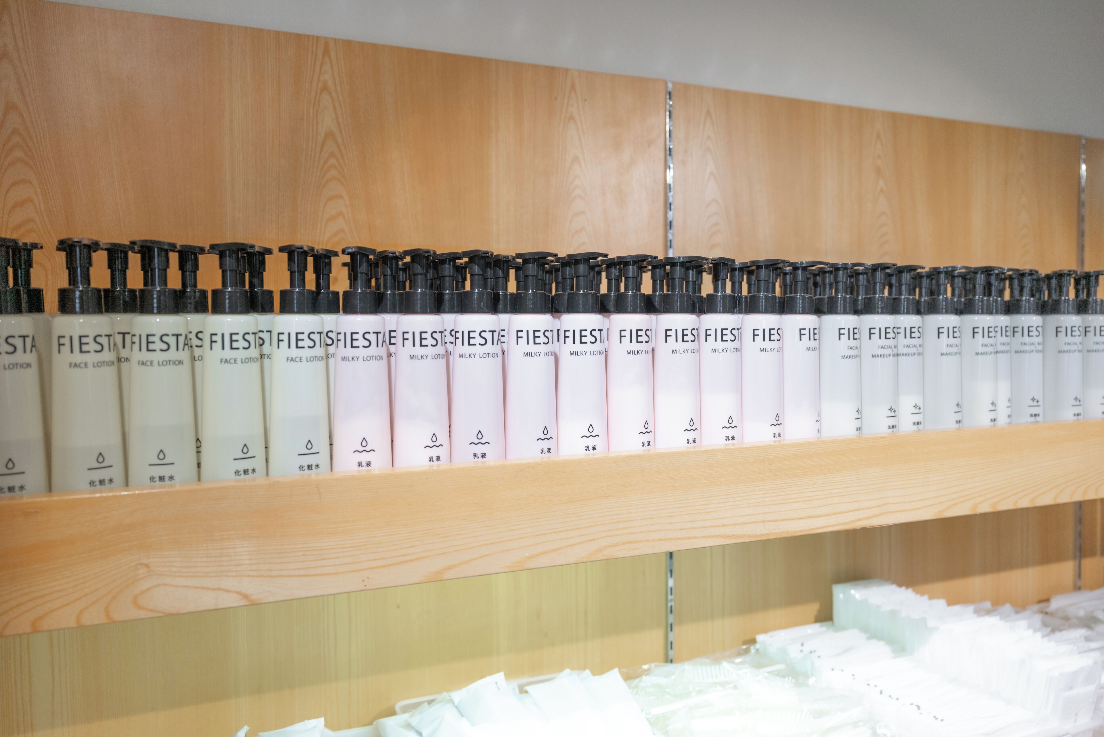 A shelf with multiple bottles of 'FIESTAS' face lotion.