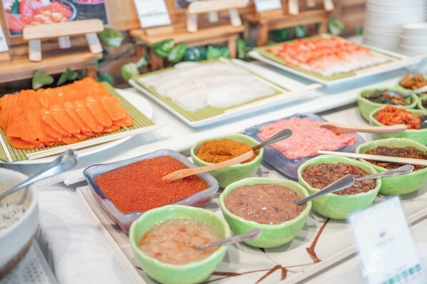 A buffet with various dishes including salmon, rice, and several condiments.