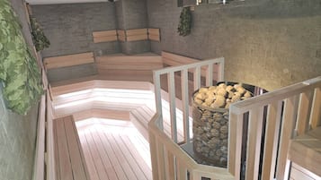 A sauna with wooden benches, a stone wall, and a metal basket filled with pebbles.