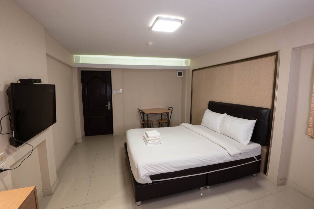 A hotel room with a bed, a TV, a desk, and a chair.