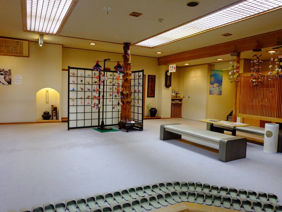 Um quarto japonês tradicional com tatames, uma mesa de madeira baixa e um shoji com enfeites pendurados.