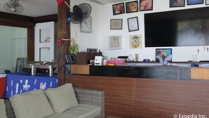 A reception area with a wooden reception desk, a large flat-screen TV, and various framed certificates and artwork on the wall. - Planet Dive (Mabini)