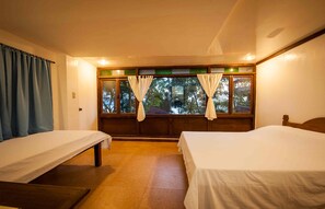 Quarto com duas camas de solteiro, janela com cortinas e vista para árvores.