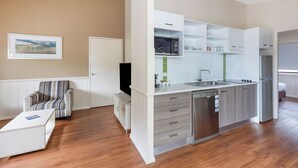 A modern kitchen with white cabinetry, a built-in microwave, and a dishwasher. - Reflections Eden - Holiday Park (Eden)