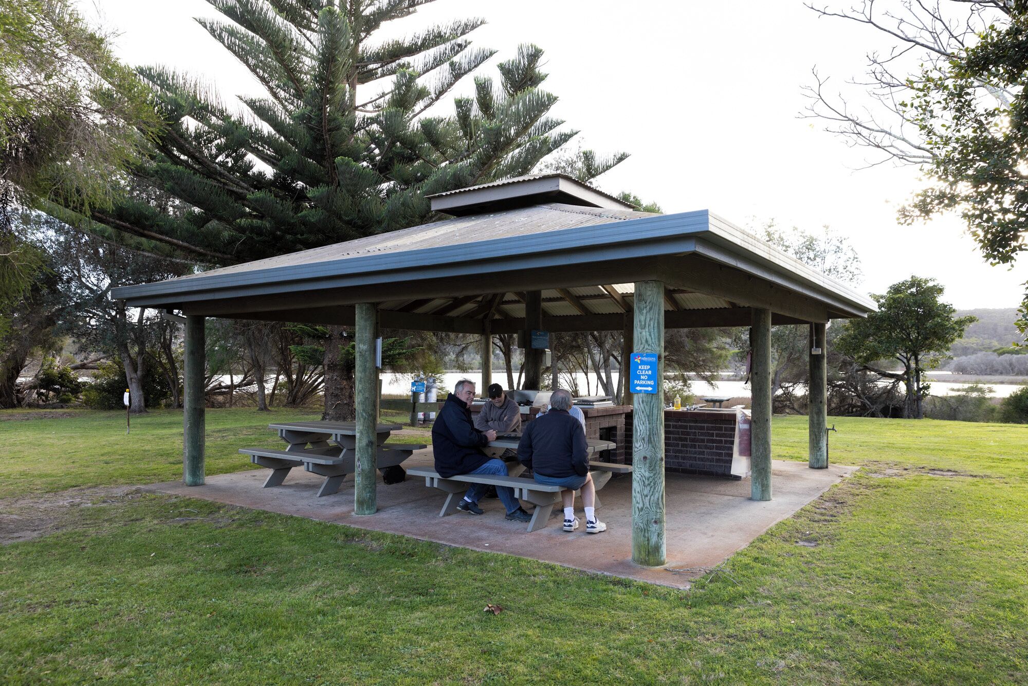 A covered picnic area with benches and a barbecue grill.