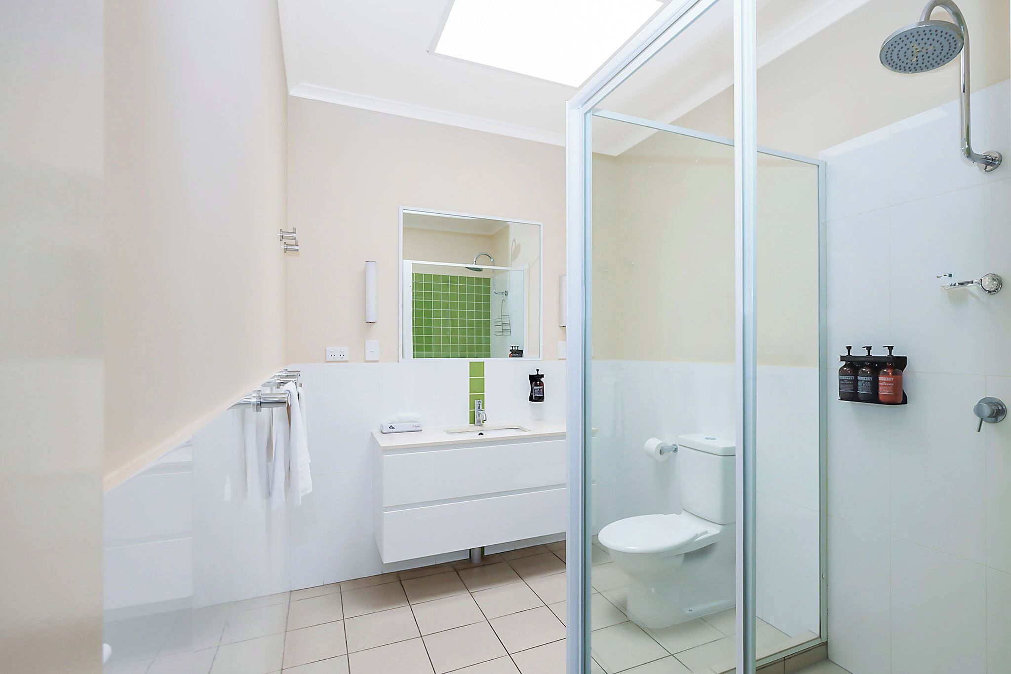 Ein modernes Badezimmer mit Duschkabine aus Glas, einem weißen Waschbecken und einer Toilette.
