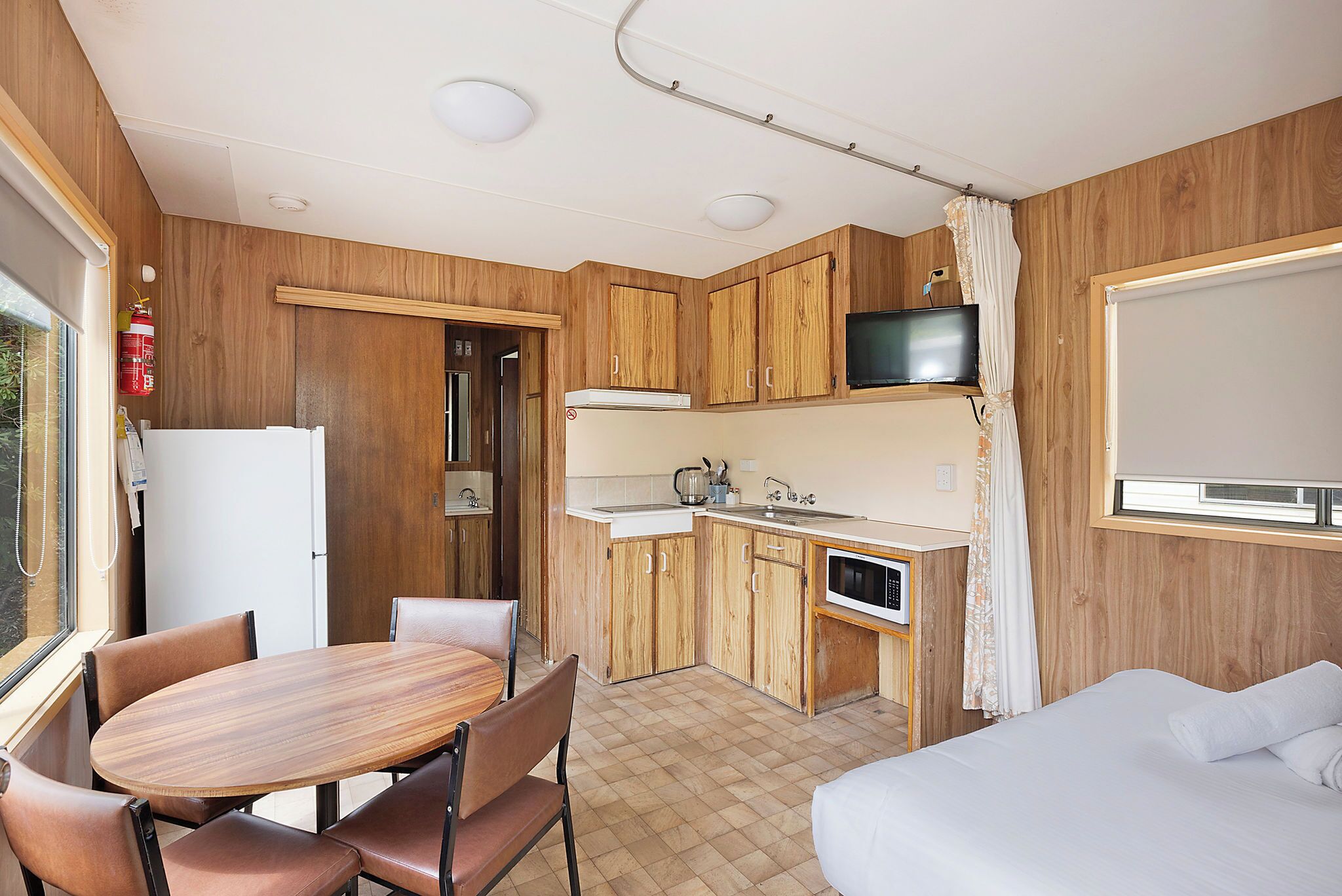 A compact kitchen with wooden cabinets, a dining table, and chairs.