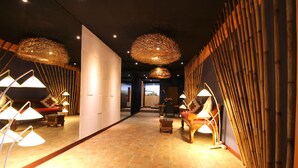 A corridor with a brick floor, modern lighting fixtures, and a view into a room with a bed and a window. - Petit Hotel Bali (Ubud)