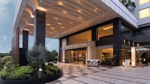Una entrada de hotel moderna con suelo de cuadros, un área de estar exterior bien iluminada y un gran letrero que dice 