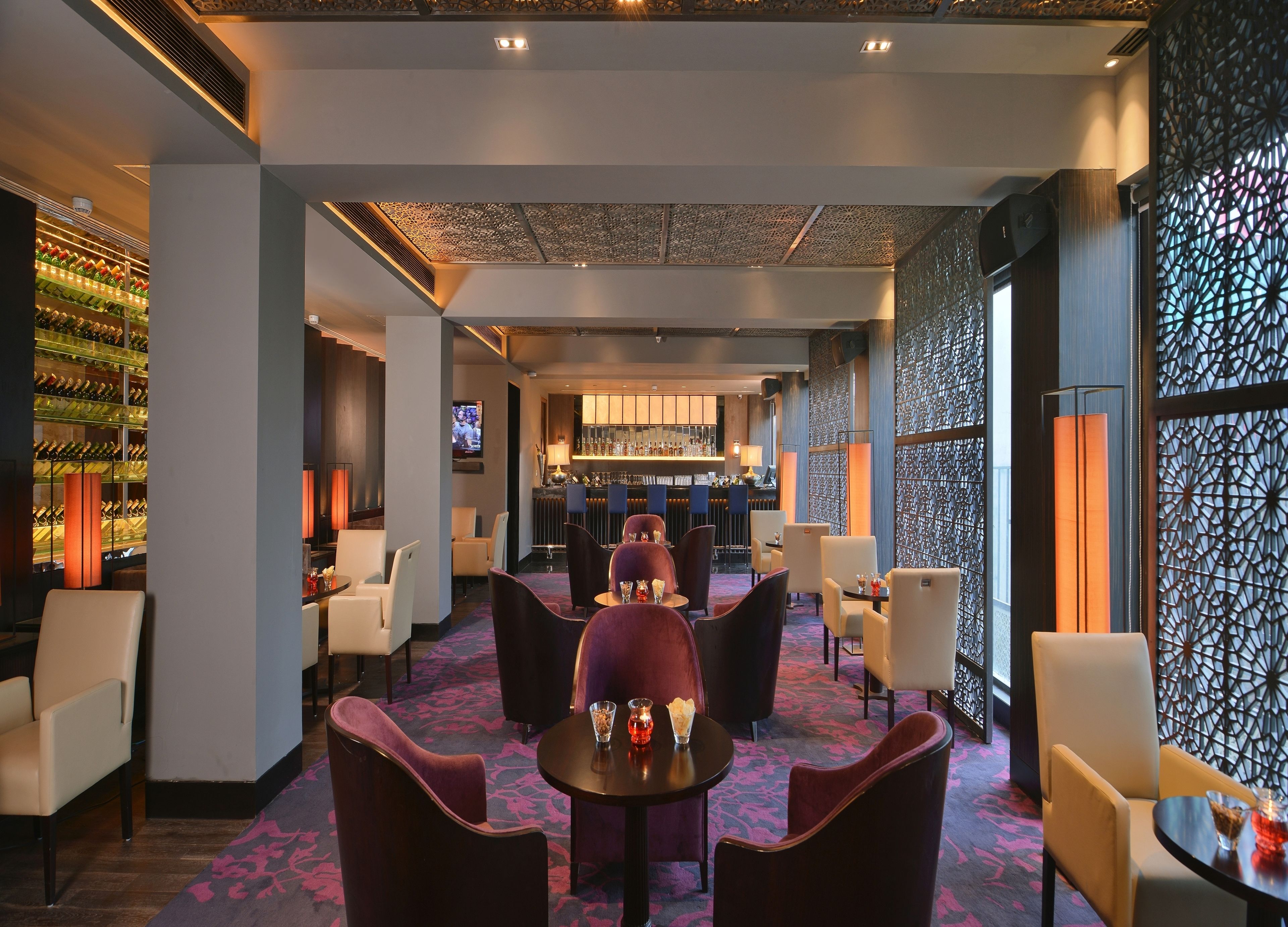 A modern bar area with a bar counter, seating, and a wine display.