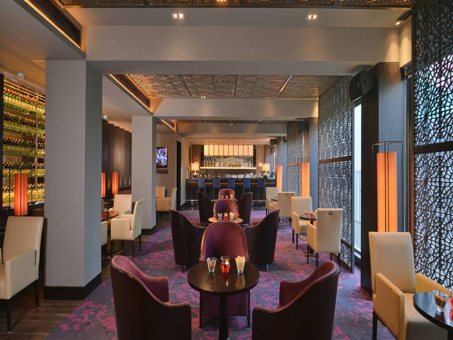A modern bar area with a bar counter, seating, and a wine display.