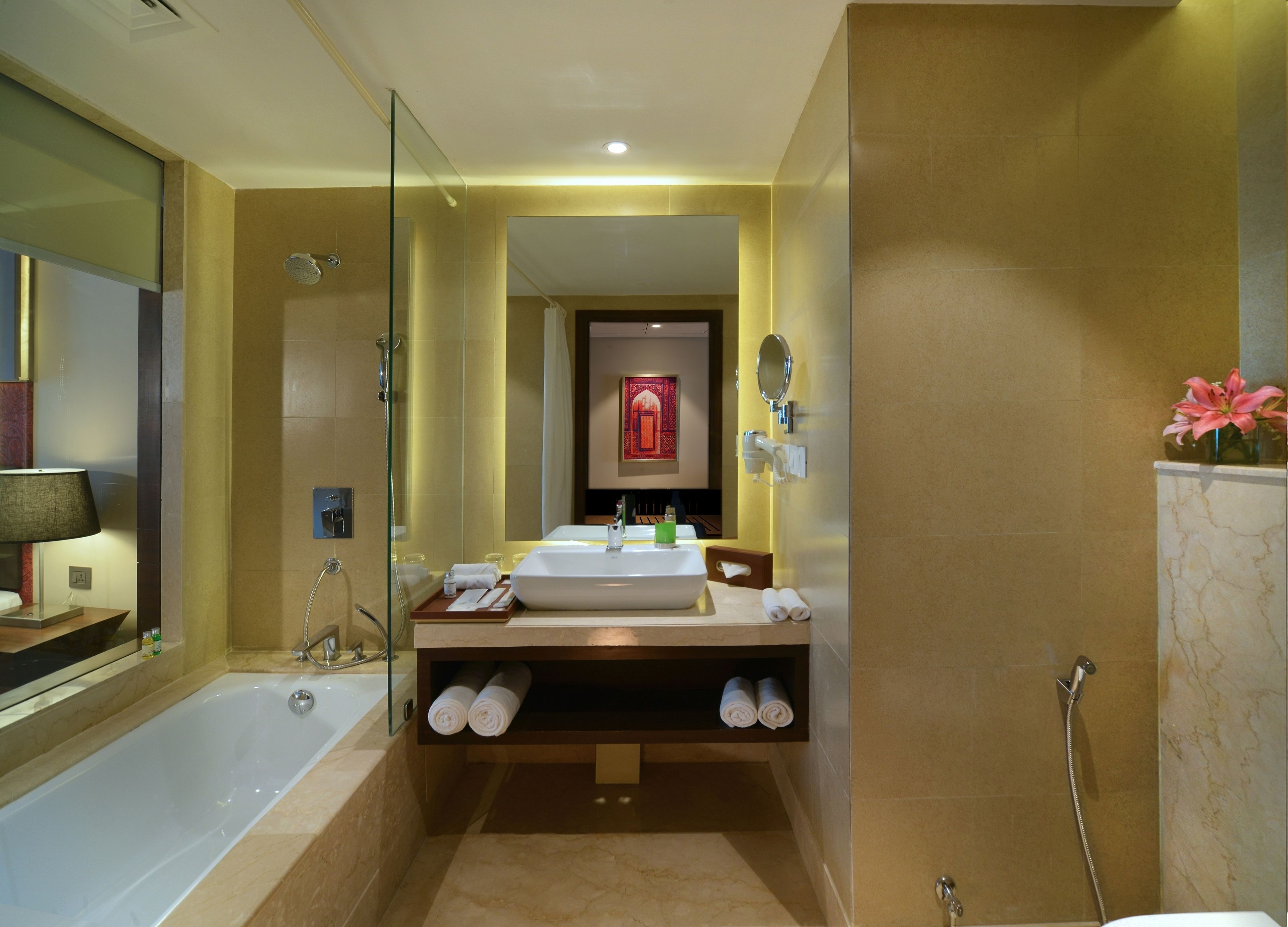 A modern bathroom with a glass-enclosed shower, a large bathtub, a vanity with a sink, and a mirror.