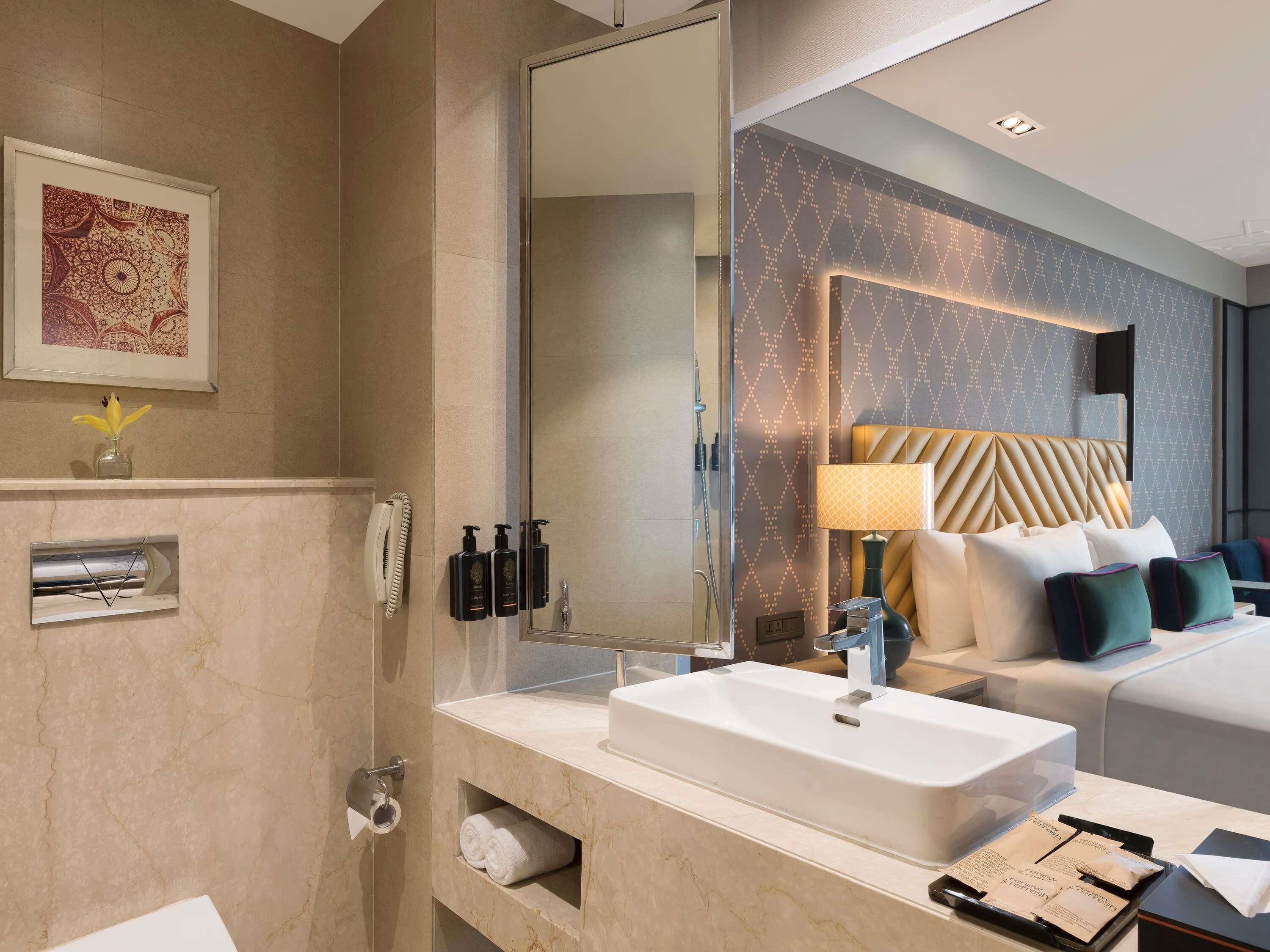 A modern bathroom with a large mirror, a white sink, and a shower.