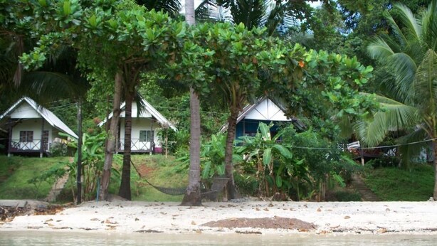 A beachfront property with several white cottages, surrounded by lush greenery and palm trees. - AoPong Resort (Ko Mak)