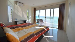 A bedroom with a bed, a desk, and a view of the sea. - AoPong Resort (Ko Mak)