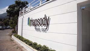 Ein Hotelschild mit dem Schriftzug "hansody" und "hotel kas" an einer weißen Wand.