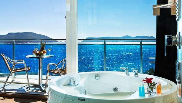 Ein Balkon mit Whirlpool, Tisch mit Früchten und Getränken und Blick aufs Meer.
