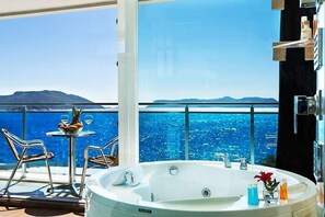 A balcony with a hot tub, a table with fruit and drinks, and a view of the sea. - Rhapsody Hotel Kaş (Kas)