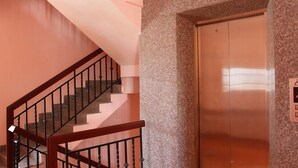 Un escalier avec une rampe en bois menant à un ascenseur.