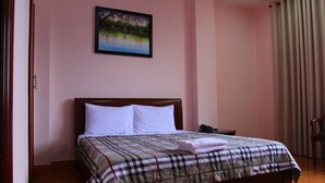 Une chambre à coucher avec un lit, une table de chevet, un tableau au mur et une fenêtre avec des rideaux.