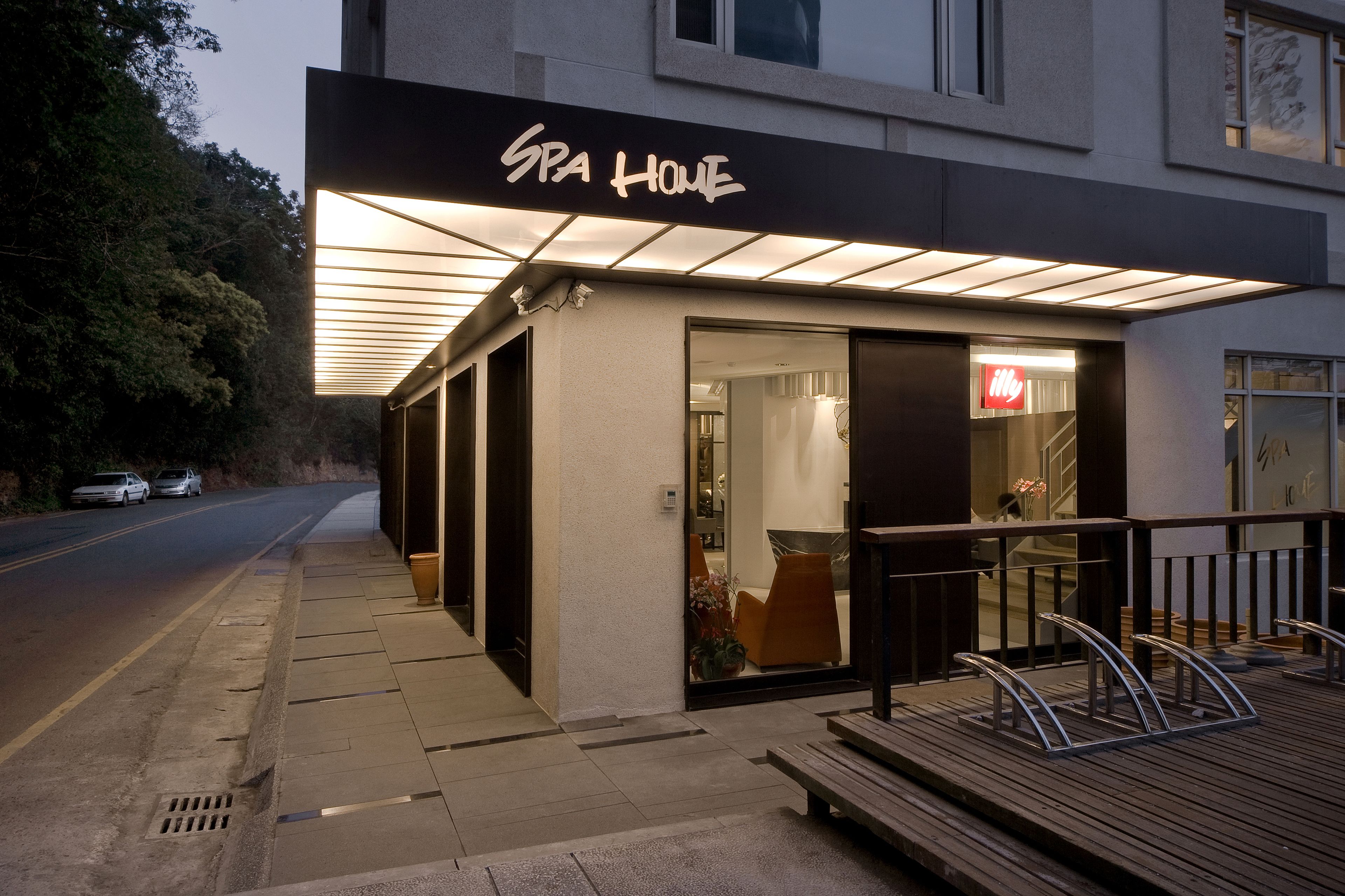 A spa house with a modern design, featuring a well-lit entrance and a visible interior through the glass doors.