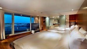 A modern hotel room with a large bed, a TV, a bathroom, and a balcony with a view of the water.