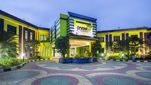A modern hotel with a prominent 'primeb' sign, featuring a circular patterned courtyard and lush landscaping.