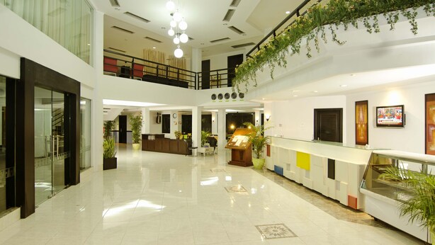 A spacious lobby with a polished floor, a reception desk, and a staircase leading to an upper level.
