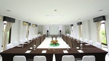 A conference room with a long table, white chairs, and a projector screen at the front.