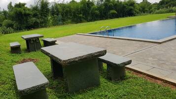 Una piscina al aire libre, sombrillas, sillones reclinables de piscina