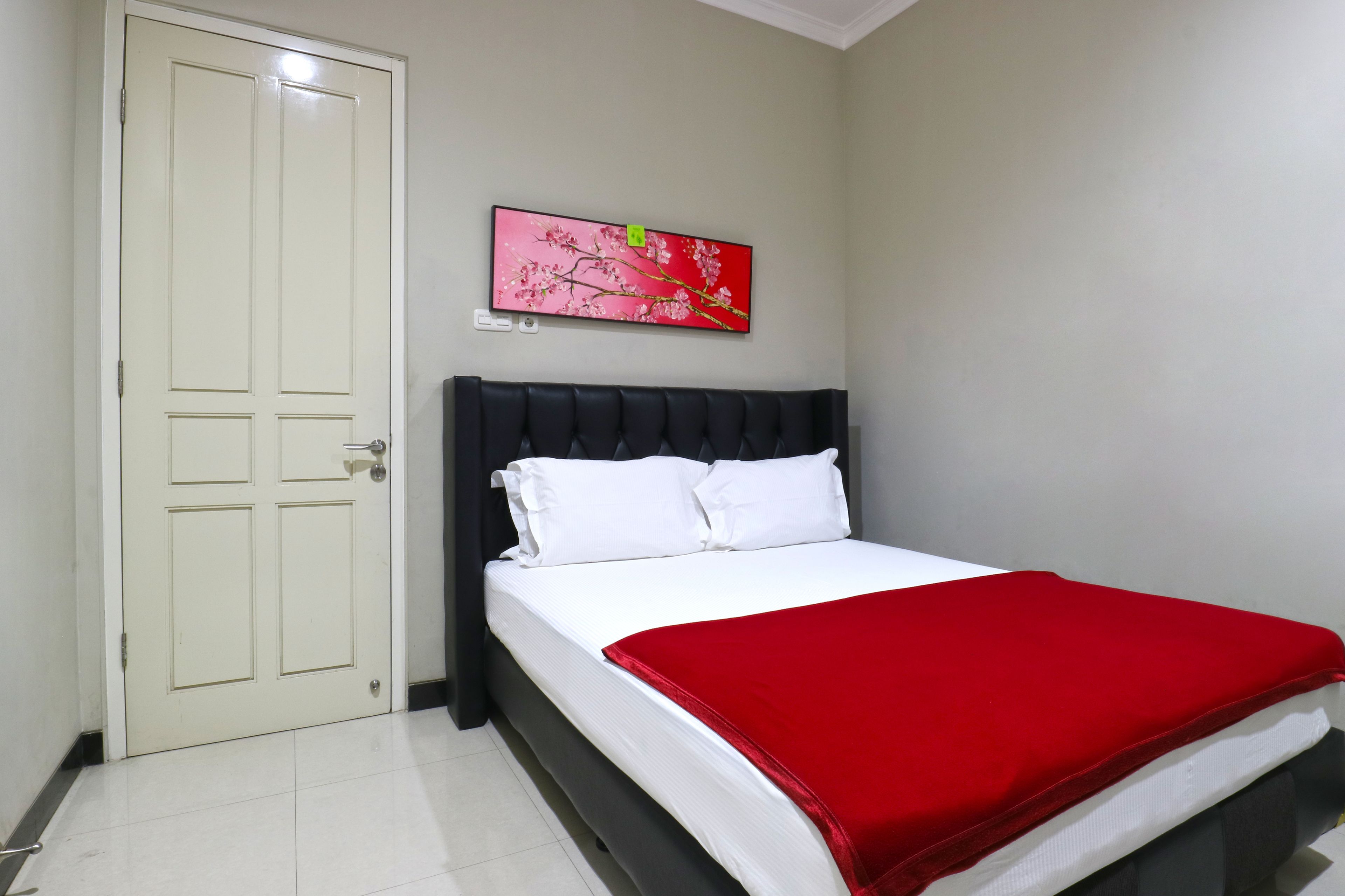 Une chambre à coucher avec un lit, une porte et un téléviseur fixé au mur.