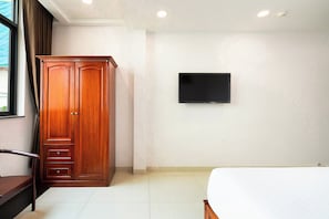 Un dormitorio con un armario de madera, un televisor de pantalla plana montado en la pared y una cama.