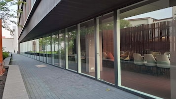 Un edificio moderno con fachada de vidrio, zona de estar al aire libre y un camino pavimentado.