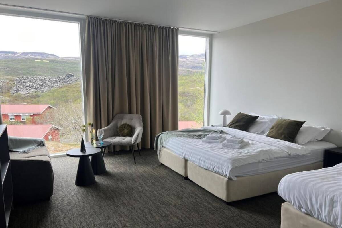Una habitación de hotel con una cama grande, una silla, una mesita y vistas del paisaje.