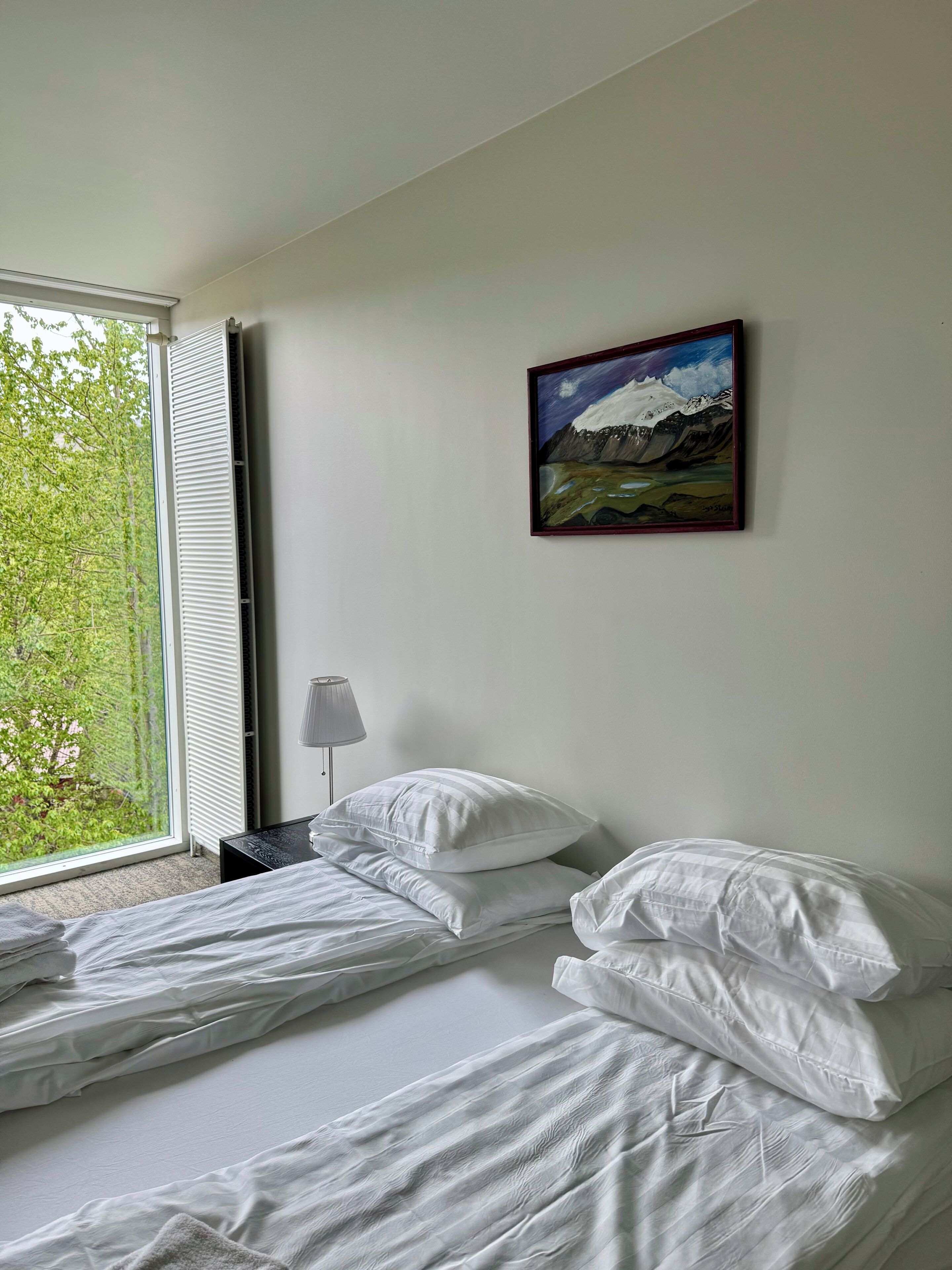 A hotel room with a bed, a lamp, and a painting on the wall.