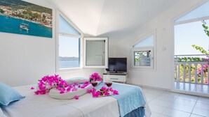 A bedroom with a bed, a TV, and a balcony with plants. - Hotel Koza (Kas)