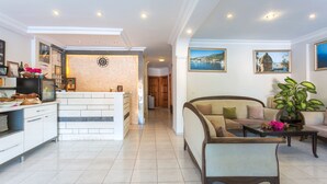 A spacious living area with a sofa, coffee table, and a kitchen area with a refrigerator and counter. - Hotel Koza (Kas)