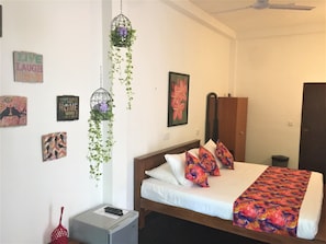 A hotel room with a bed, a wardrobe, and wall decorations including framed pictures and a sign. - Anara Villa (Unawatuna)