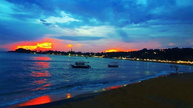 A coastal sunset with boats on the water and a beach in the foreground. - Anara Villa (Unawatuna)