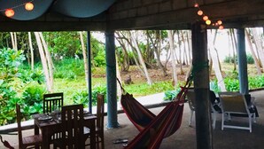 A covered outdoor seating area with a hammock, chairs, and string lights. - Anara Villa (Unawatuna)
