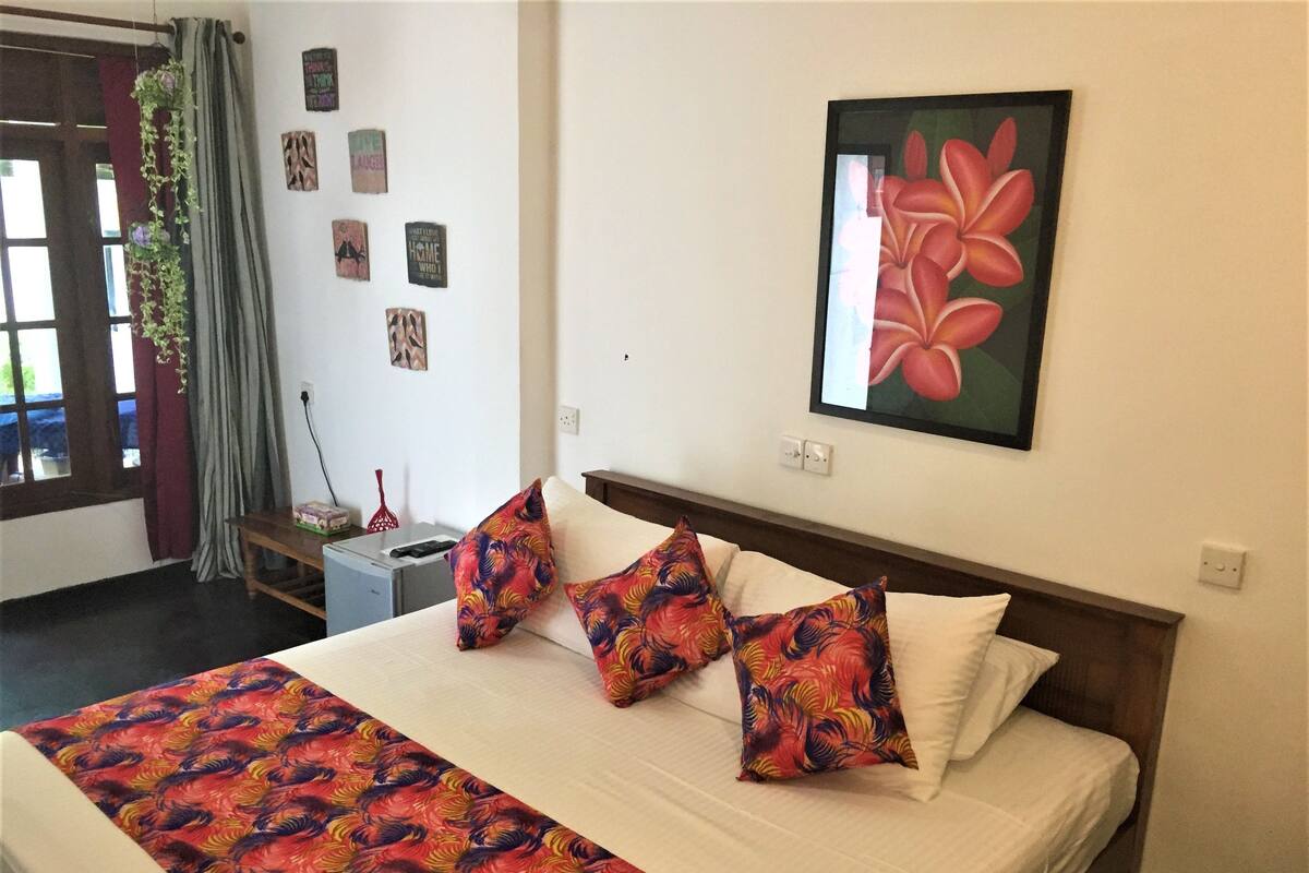A hotel room with a bed, a desk, and a window with curtains.