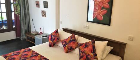 A hotel room with a bed, a desk, and a window with curtains.