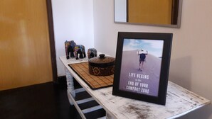 A white wooden table with a framed picture of a person walking on sand, a decorative box, and colorful elephant figurines. - Anara Villa (Unawatuna)