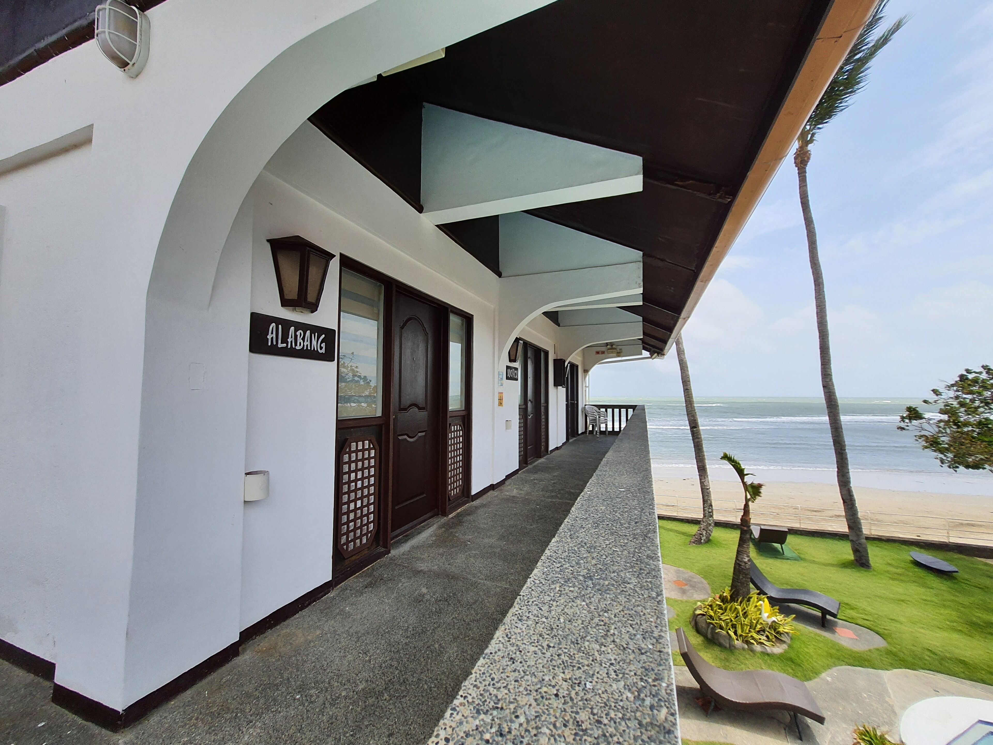 Un hôtel doté d’une galerie couverte, d’une enseigne indiquant « ALABANG » et offrant une vue sur la plage.