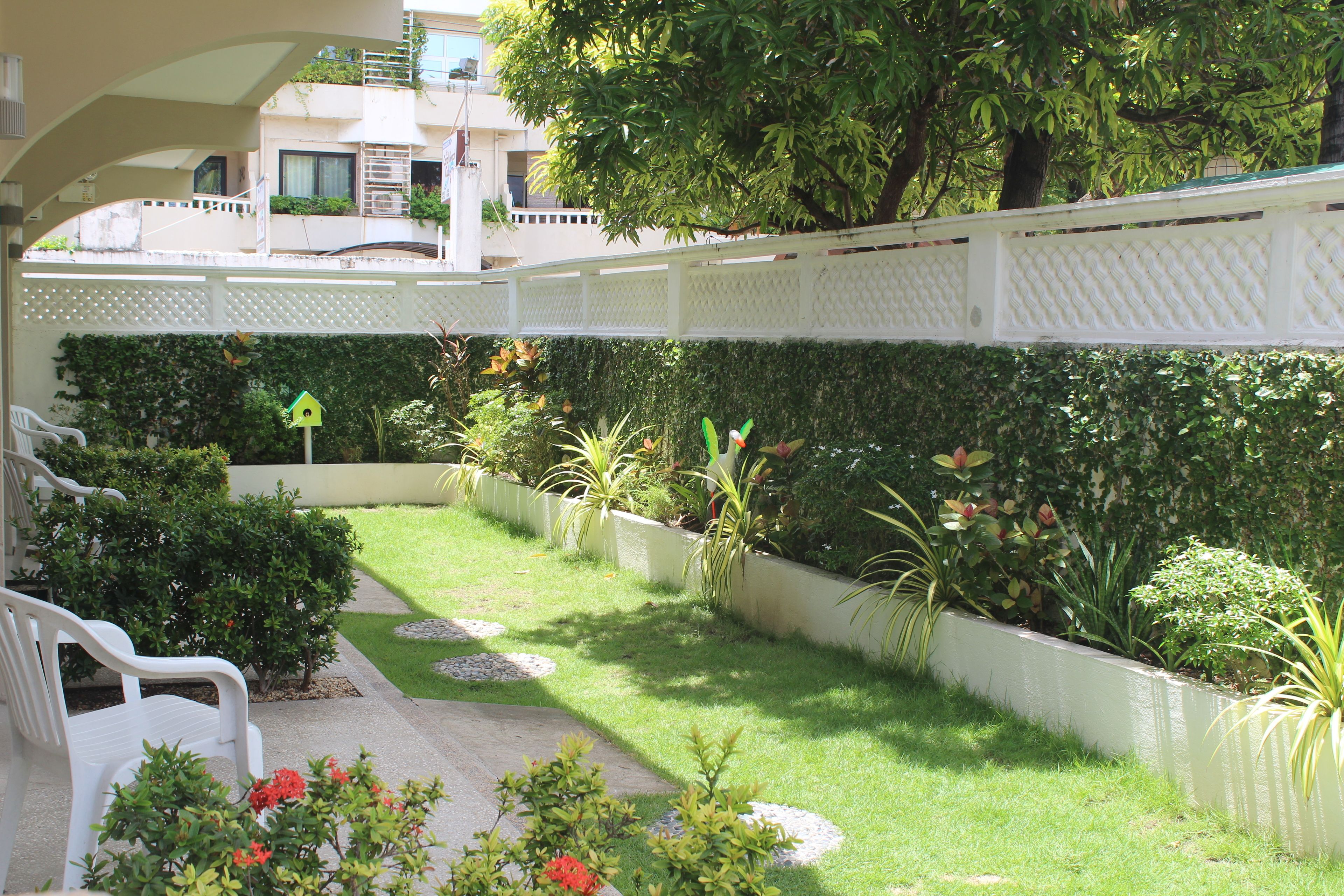 Un jardin bien entretenu, avec une clôture blanche, un chemin et un banc.