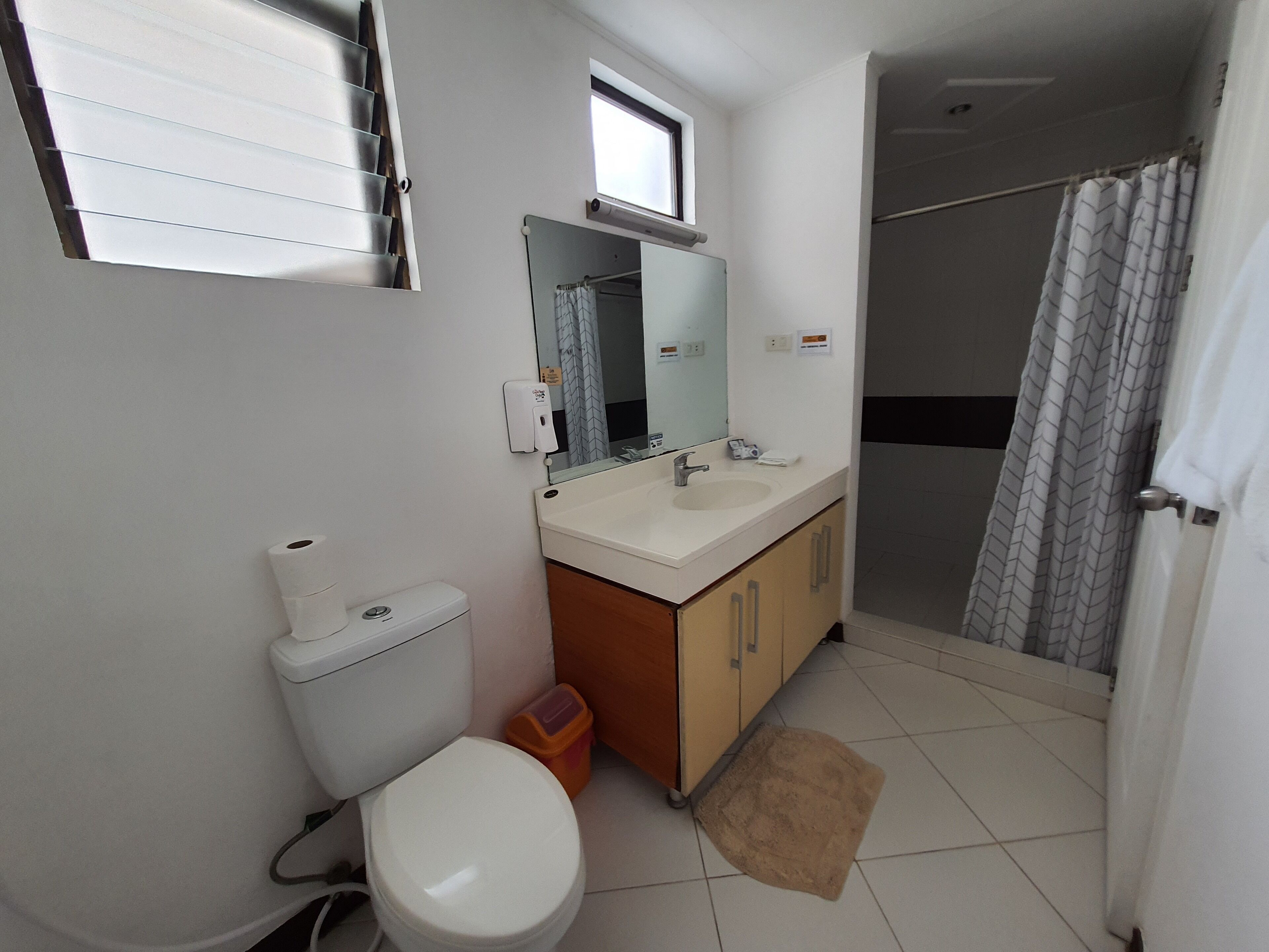 Un baño con inodoro, lavamanos, espejo y cortina de ducha.