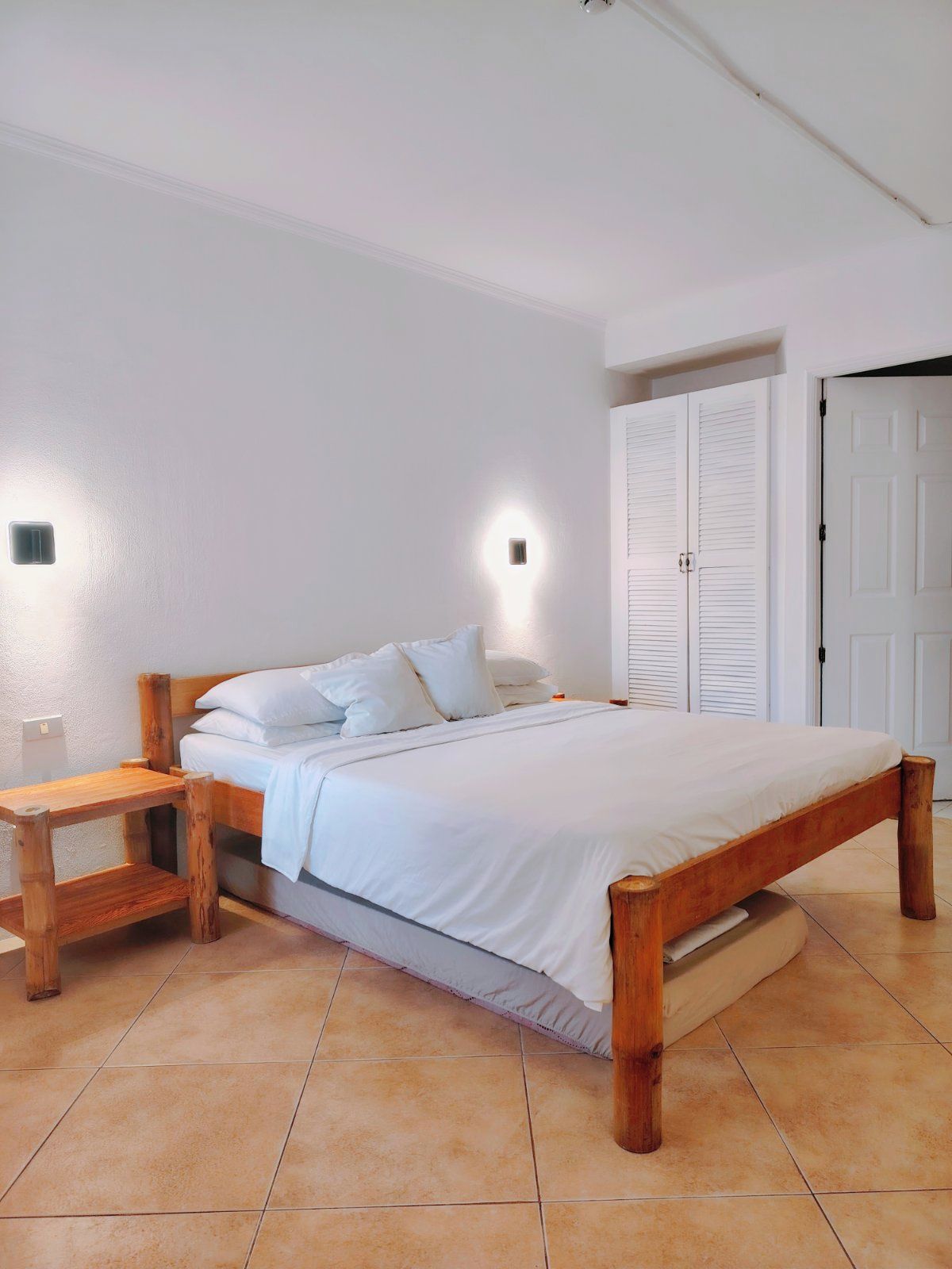 Une chambre à coucher avec un lit en bois, une table de chevet et une armoire.