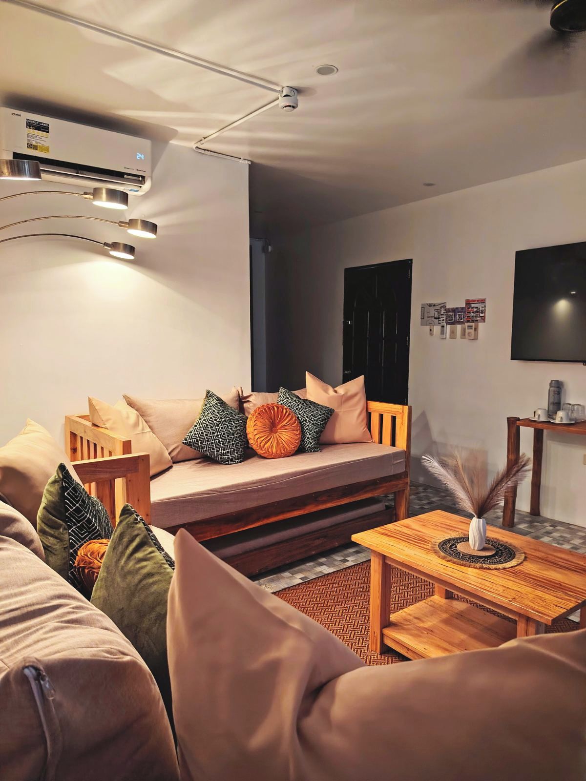 A modern living room with a sofa, a coffee table, and a flat-screen TV mounted on the wall.
