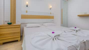 Habitación de hotel con cama, cómoda de madera, un cuenco sobre la cómoda y aire acondicionado instalado en la pared.