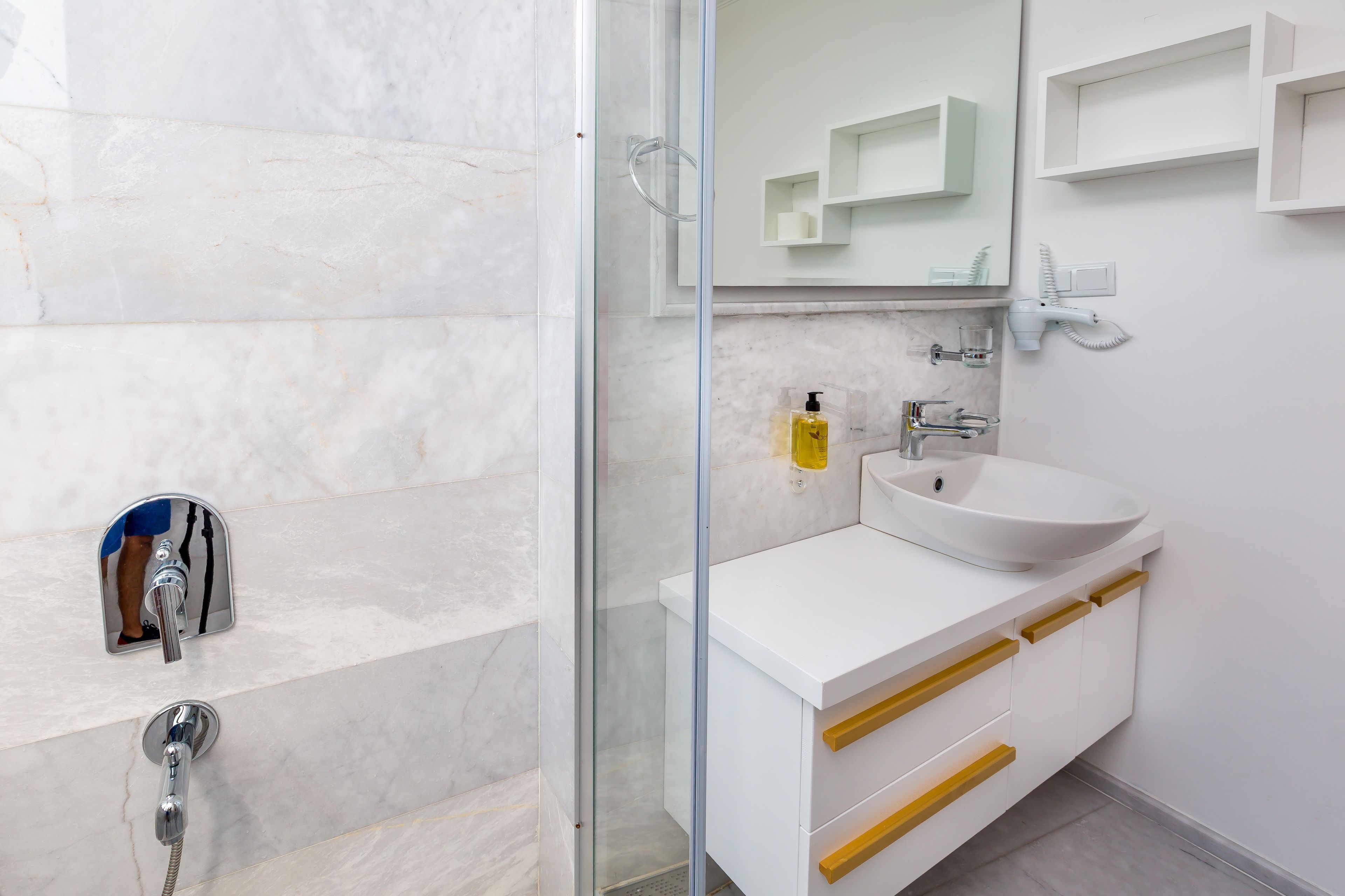 A modern bathroom with a glass-enclosed shower, a white sink, and a mirror above the sink.